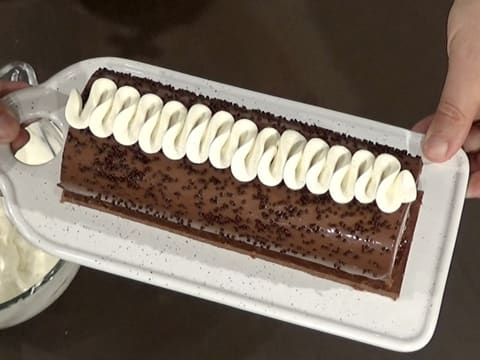 Obtention du gâteau forêt noire décoré avec la crème Chantilly vanille sur son plat de service