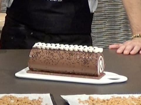 Vue de face du gâteau forêt noire sur sont plat de service sur le plan de travail, et décoré avec la Chantilly vanille