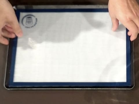 Un tapis de cuisson en silicone est placé sur une plaque à pâtisserie elle-même posée sur le plan de travail