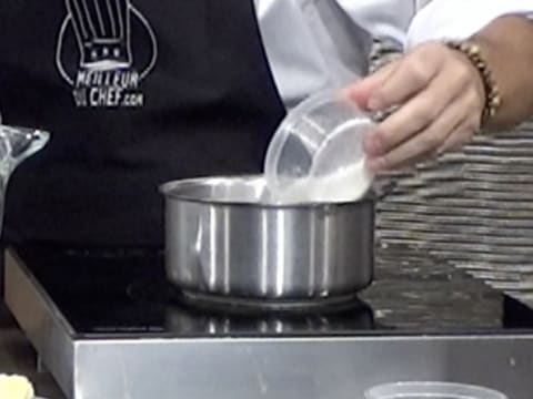 Ajout du sucre en poudre dans la casserole qui est sur la plaque de cuisson