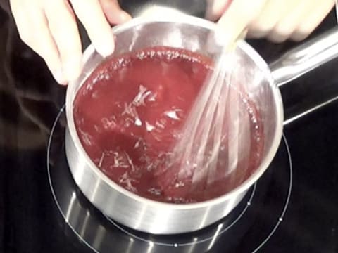 La préparation à la griotte contenue dans la casserole est mélangée au fouet