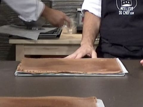 Le biscuit à pâte à choux au chocolat qui est placé sur la plaque à pâtisserie, est posé sur le plan de travail