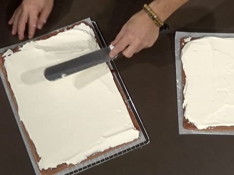 La Chantilly vanille est étalée sur toute la surface du second biscuit au chocolat, à l'aide de la spatule métallique coudée