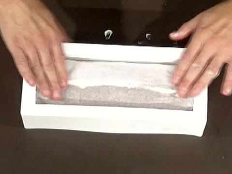 Le gâteau enroulé dans la feuille de papier sulfurisé est placé dans le moule à bûche en silicone