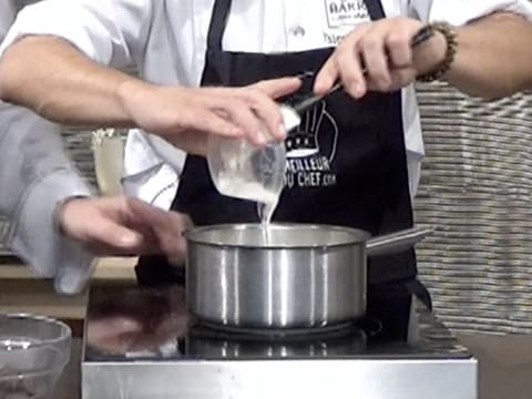 Le sirop de glucose est versé dans une casserole qui est posée sur une plaque de cuisson