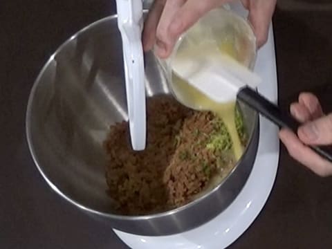 Ajout du mélange beurre fondu, chocolat blanc et beurre de cacao dans la cuve du batteur, sur le crumble