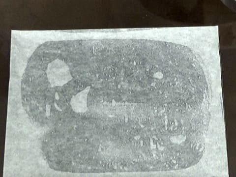 Une feuille de papier sulfurisé graissée est placée sur une plaque à pâtisserie