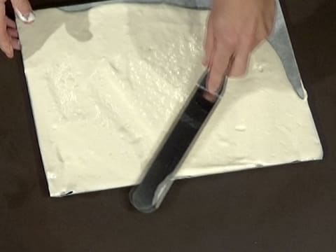 La pâte à biscuit fromage blanc est étalée jusqu'aux bords de la plaque à pâtisserie, avec une spatule métallique coudée