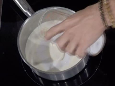 Ajout du sucre en poudre dans la casserole, sur la crème liquide