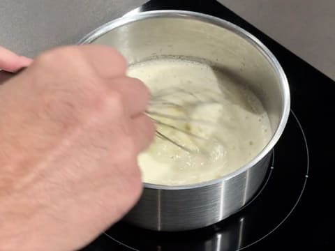 La casserole contenant la préparation lactée est placée sur la plaque de cuisson, et le mélange est fait à l'aide du fouet