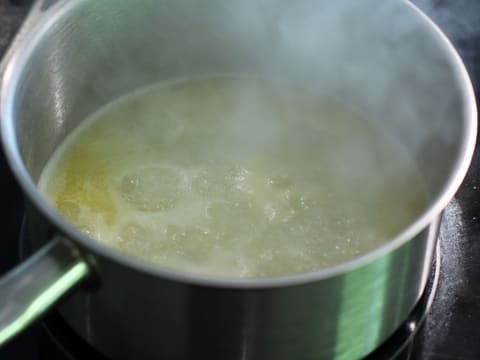 L'eau et le beurre fondu sont en ébullition dans la casserole sur la plaque de cuisson