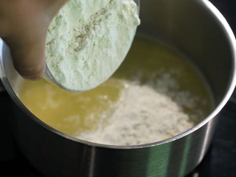 Ajout de la farine dans l'eau et le beurre fondu qui se trouvent dans la casserole