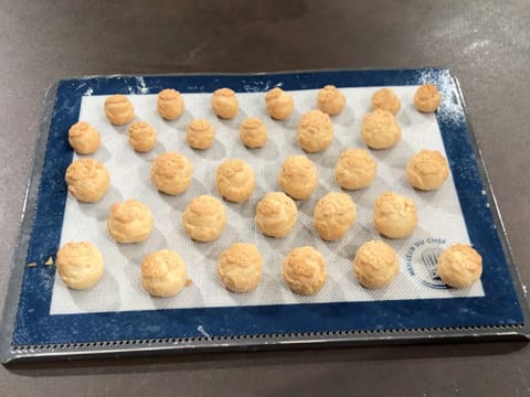 Obtention des choux cuits et dorés sur la plaque de cuisson perforée recouverte d'un tapis de cuisson en silicone