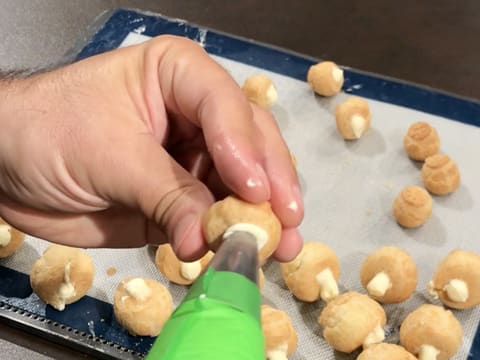 À l'aide de la poche à douille, un petit chou est fourré de crème diplomate