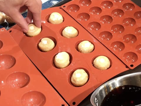 Les gros choux trempés dans le caramel sont placés dans les empreintes d'un moule silicone dont le diamètre des demi sphères est légèrement supérieur aux choux