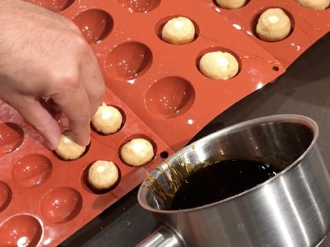 Les petits choux trempés dans le caramel sont placés dans les empreintes d'un moule silicone dont le diamètre des demi sphères est légèrement supérieur aux choux