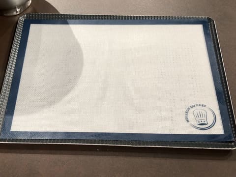 Une plaque à pâtisserie recouverte d'un tapis de cuisson silicone sur le plan de travail