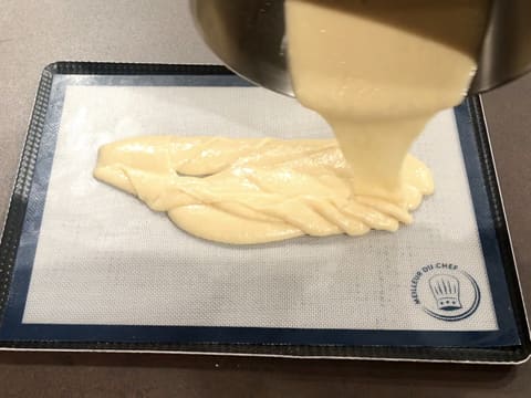 La pâte à biscuit moelleux aux amandes est versée sur le tapis de cuisson silicone