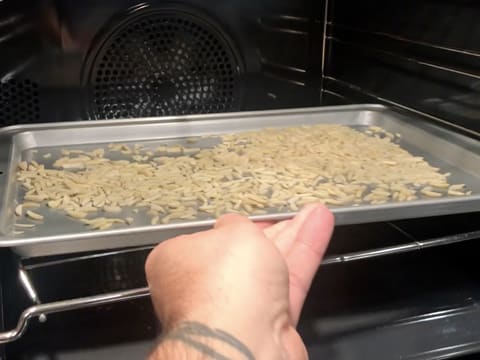 Les amandes en bâtonnets sur la plaque à pâtisserie sont placées dans le four