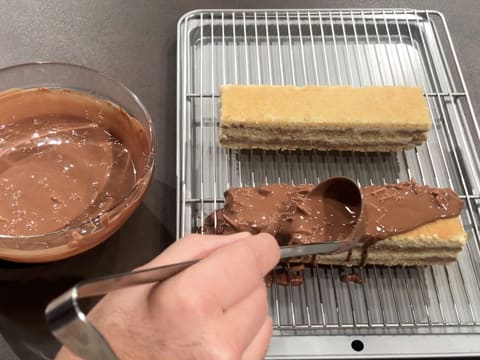 Nappage du premier gâteau avec le glaçage au chocolat au lait rocher, à l'aide d'une louche