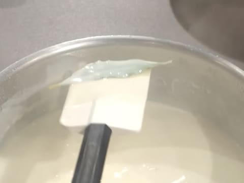 Retrait d'une feuille de laurier de la sauce béchamel qui se trouve dans la casserole