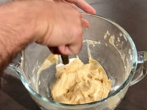 Les parois de la cuve du batteur qui contient l'appareil à madeleines sont cornées à l'aide de la spatule maryse