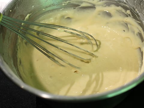 Mélange de la pâte à madeleines dans le cul de poule, à l'aide d'un fouet