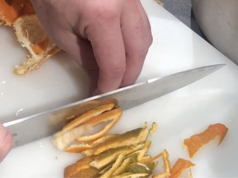 Les écorces des clémentines sont finement taillées à l'aide d'un grand couteau de cuisine, sur une planche à découper