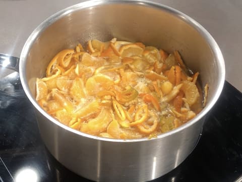 Les lanières d'écorce et les segments des clémentines sont en train de cuire dans la casserole