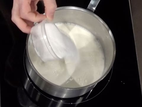 Le sucre en poudre est versé dans la casserole, sur le lait