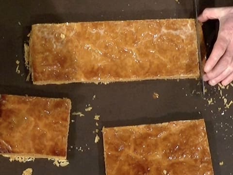 L'extrémité de la seconde bande de pâte feuilletée cuite est parée au couteau