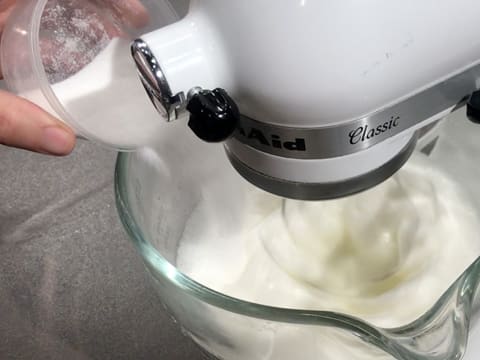 Le sucre en poudre est versé sur les blancs d'oeufs qui sont fouettés dans la cuve du batteur muni de l'accessoire fouet et qui deviennent mousseux