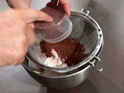 Le cacao en poudre est versé sur la farine dans une passoire fine, au-dessus de la cuve du batteur
