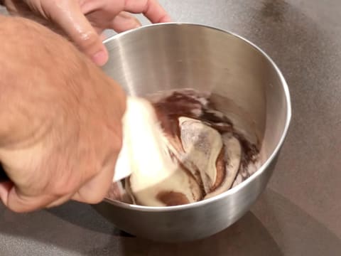 La farine et le cacao en poudre sont incorporés dans la préparation mousseuse à l'aide de la spatule maryse