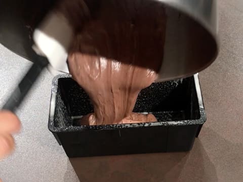 L'appareil à génoise au chocolat est versé dans le moule à pain de mie graissé