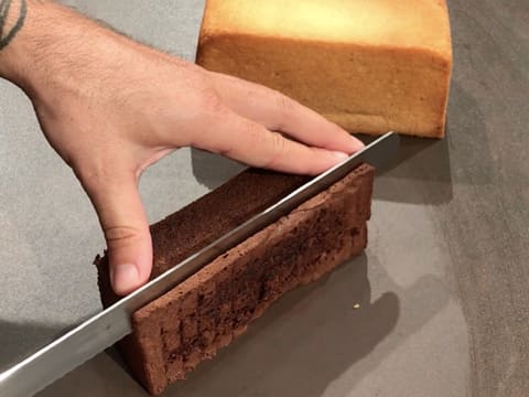 La génoise au chocolat est parée sur un côté, à l'aide d'un couteau-scie à génoise