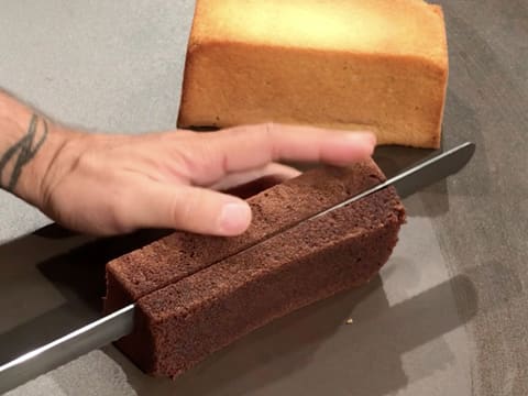 Une tranche de génoise au chocolat est coupée avec le couteau-scie à génoise