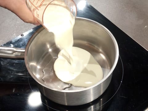 La crème fleurette est versée sur le sirop de glucose dans une casserole qui est placée sur la plaque de cuisson