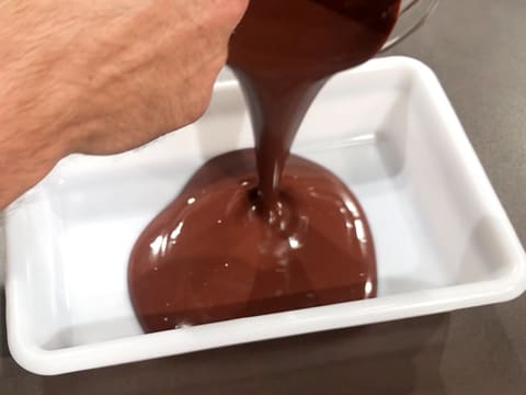 La ganache au chocolat est versée dans un bac alimentaire