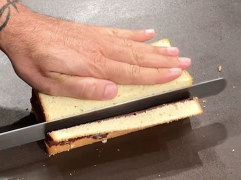 La croûte d'un côté du gâteau est retirée avec un couteau-scie à génoise