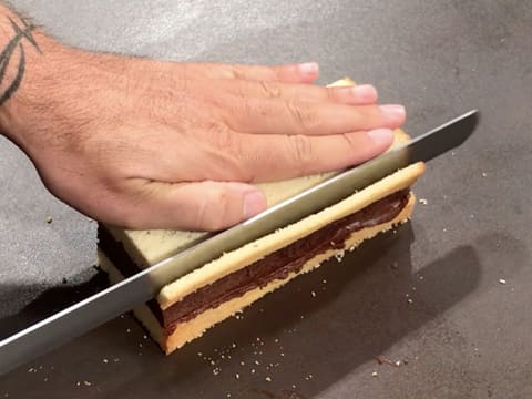 Un côté du gâteau est paré avec le couteau-scie à génoise