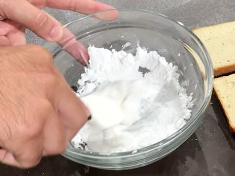 Mélange du sucre glace et de l'eau dans le saladier, à l'aide d'une spatule type maryse