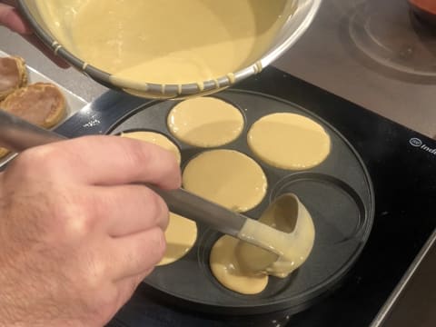 La pâte à pancakes est versée dans les empreintes d'une poêle à blinis et à pancakes