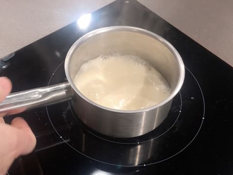 La préparation à base de lait concentré entre en ébullition dans la casserole qui est sur la plaque de cuisson