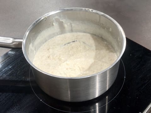 Le riz rond est en train de cuire dans le lait qui est dans la casserole sur la plaque de cuisson