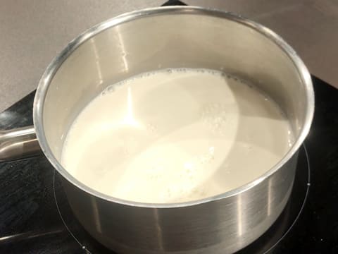 Le lait entier est en train de cuire dans une casserole posée sur une plaque de cuisson