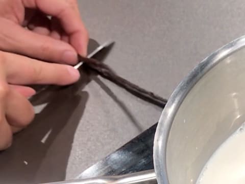 Une gousse de vanille est fendue en deux dans le sens de la longueur, à l'aide d'un couteau de cuisine