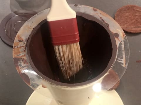 Punchage du biscuit chocolat qui se trouve dans le cône en chocolat, à l'aide d'un pinceau pâtissier