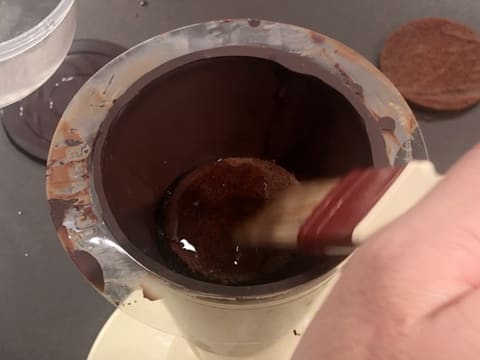 Punchage du biscuit chocolat qui se trouve dans le cône en chocolat, à l'aide d'un pinceau pâtissier