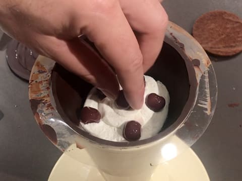 Six cerises à l'eau de vie sont piquées dans la Chantilly dans le cône en chocolat